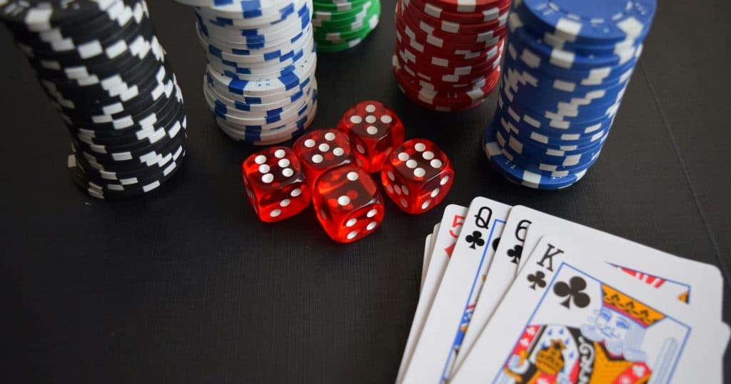 poker playing cards, dice and poker chips on a table