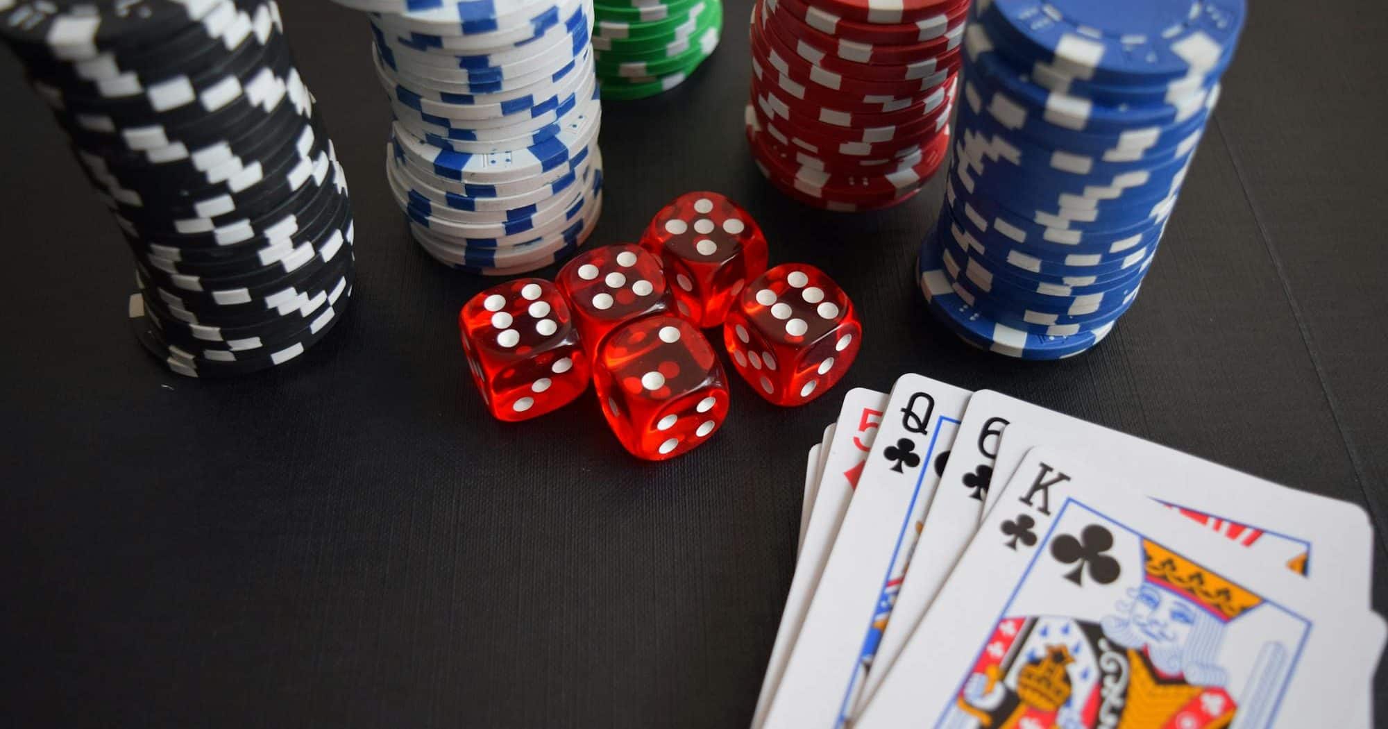 poker playing cards, dice and poker chips on a table