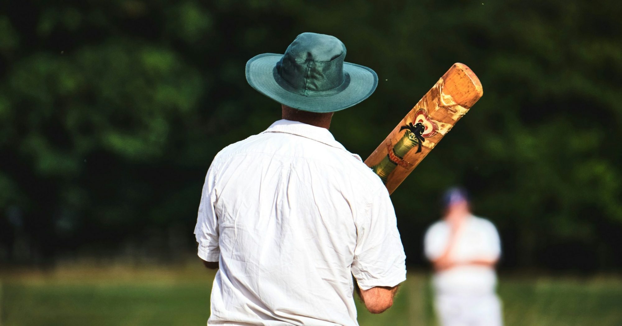 Man with a cricket bat and a hat