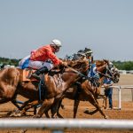 Multiple horses racing with people on top of them