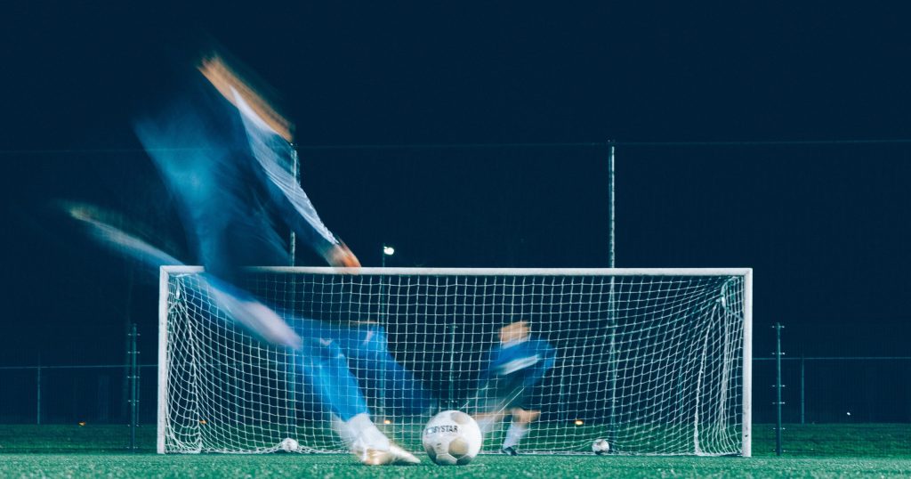 Man kicking a football ball into the goal