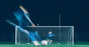 Man kicking a football ball into the goal