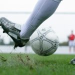Man kicking a football ball in the football field