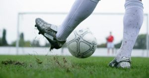Man kicking a football ball in the football field