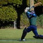 Man getting ready to strike a cricket ball