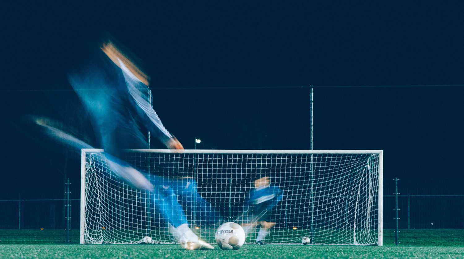 Man kicking a ball in the net