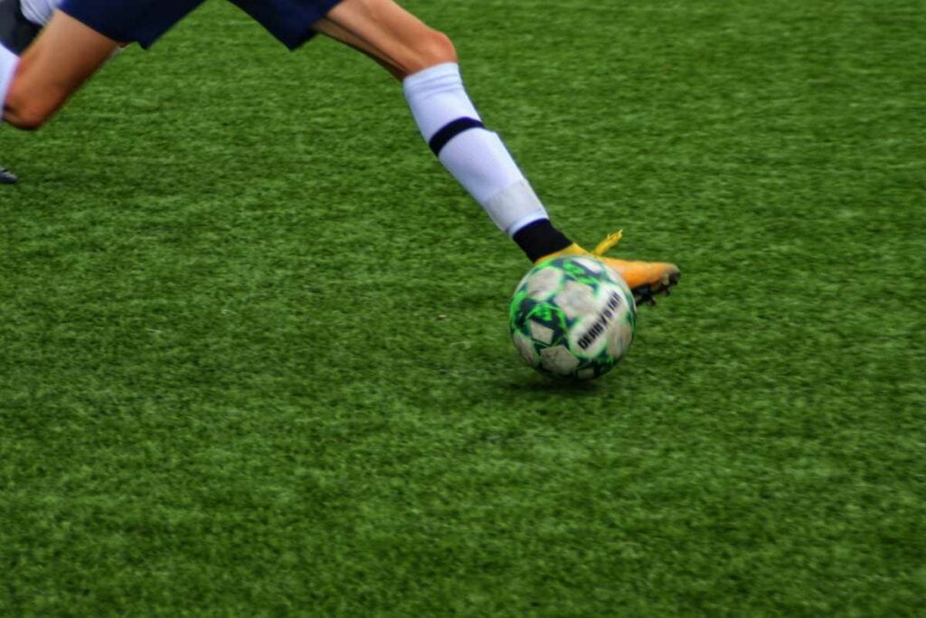 Man kicking a football ball on the field