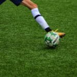 Man kicking a football ball on the field
