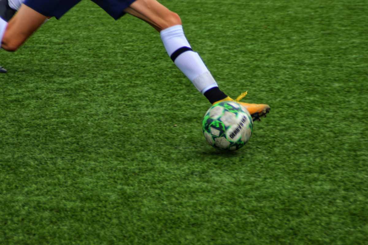 Man kicking a football ball on the field