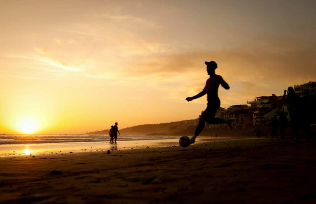 Man kicking a football ball in the beach