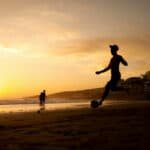 Man kicking a football ball in the beach